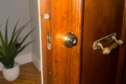 Puerta de madera de una vivienda con cerradura de cilindro y tirador de latón